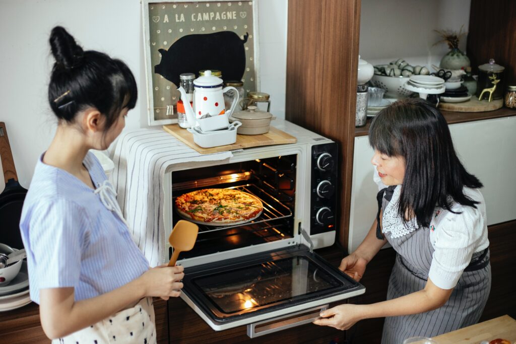 The picture depicts two women using rack for baking pizza instead of cardboard.
